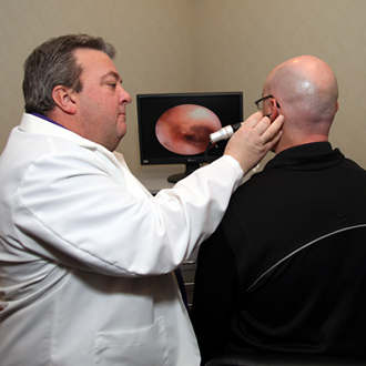 hearing specialist examining man's ear with tool